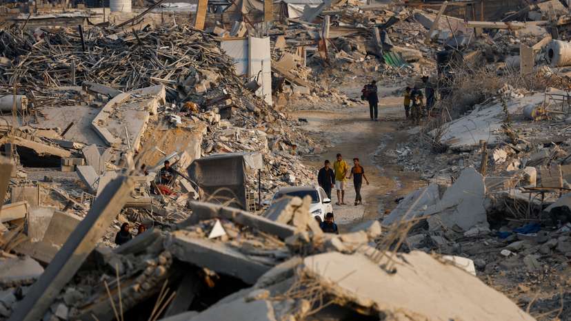 Palestinians walk past the rubble of destroyed buildings in Jabalia