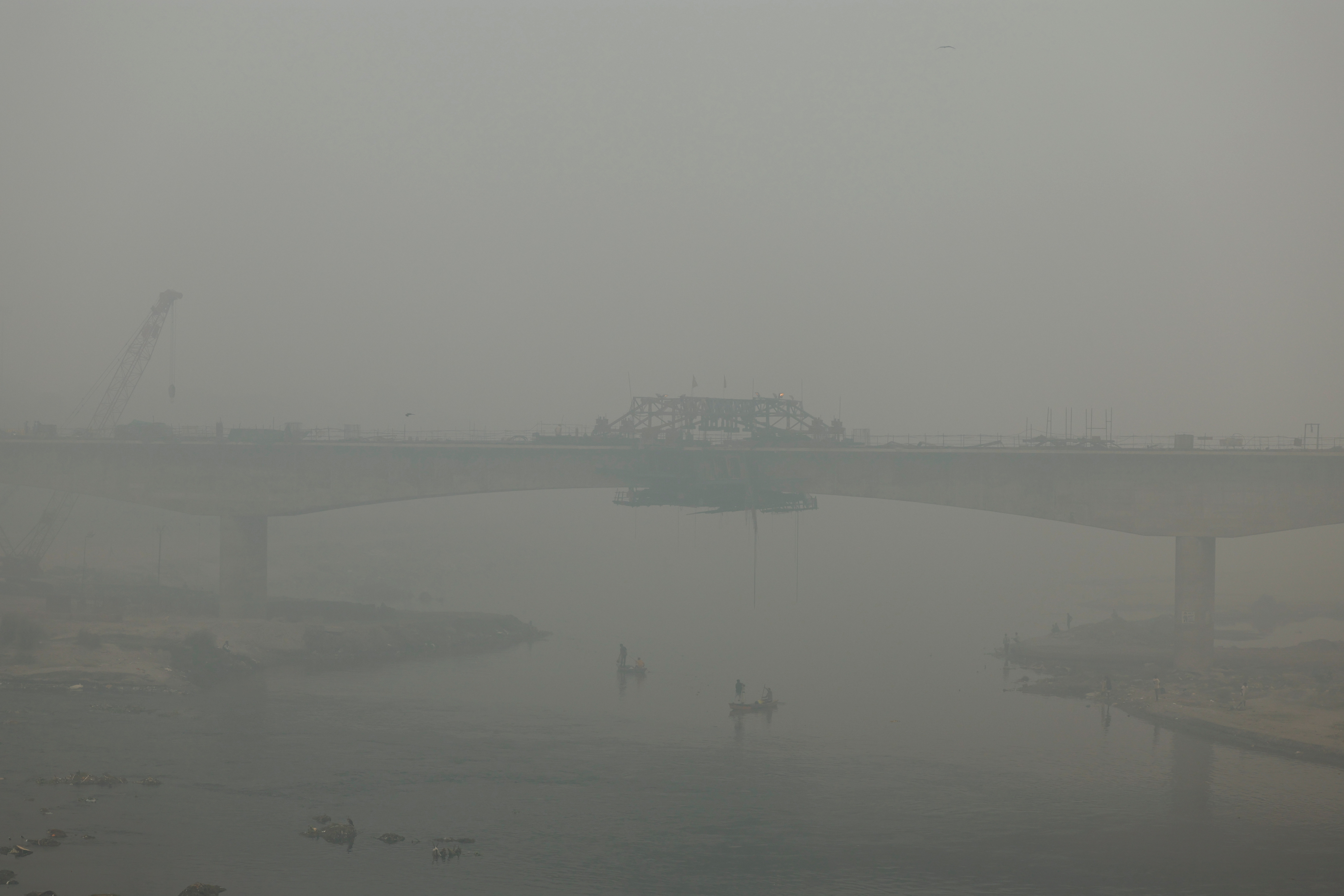 People ride on a boat on the river Yamuna, as the sky is enveloped with smog after Delhi's air quality turned "hazardous" due to alarming air pollution, in New Delhi
