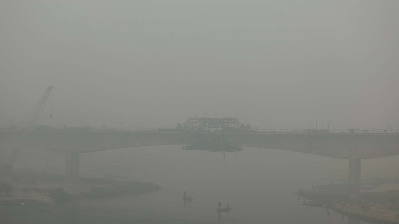 People ride on a boat on the river Yamuna, as the sky is enveloped with smog after Delhi's air quality turned "hazardous" due to alarming air pollution, in New Delhi