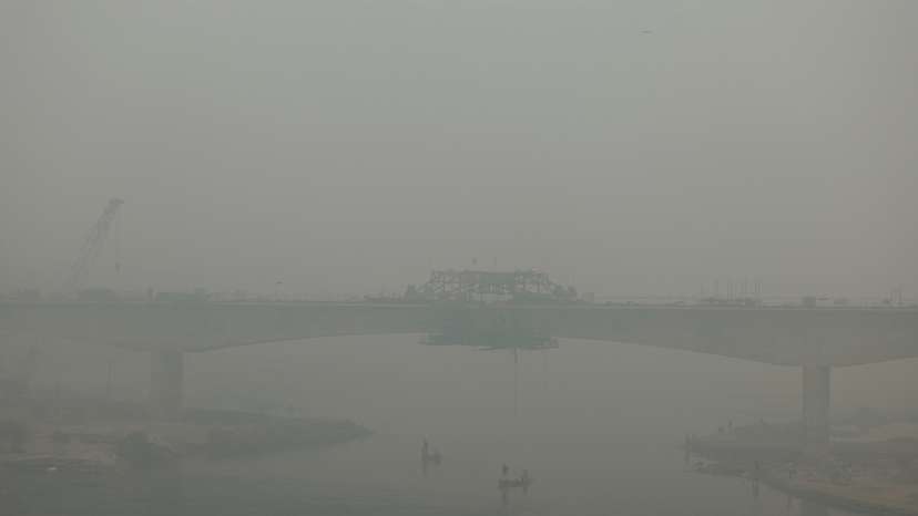 People ride on a boat on the river Yamuna, as the sky is enveloped with smog after Delhi's air quality turned "hazardous" due to alarming air pollution, in New Delhi