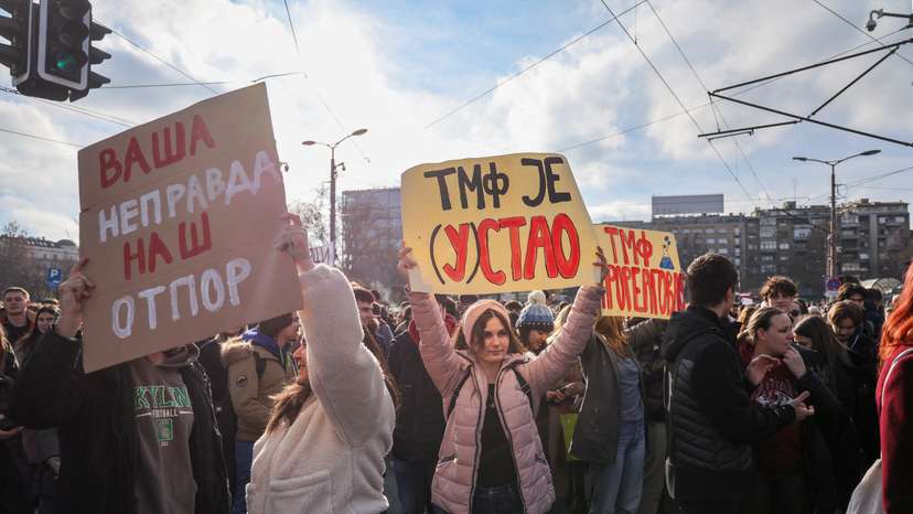 Students hold banners as they block the road for fifteen minutes to pay their respect for fifteen victims of a fatal roof collapse at Novi Sad's railway station, in Belgrade