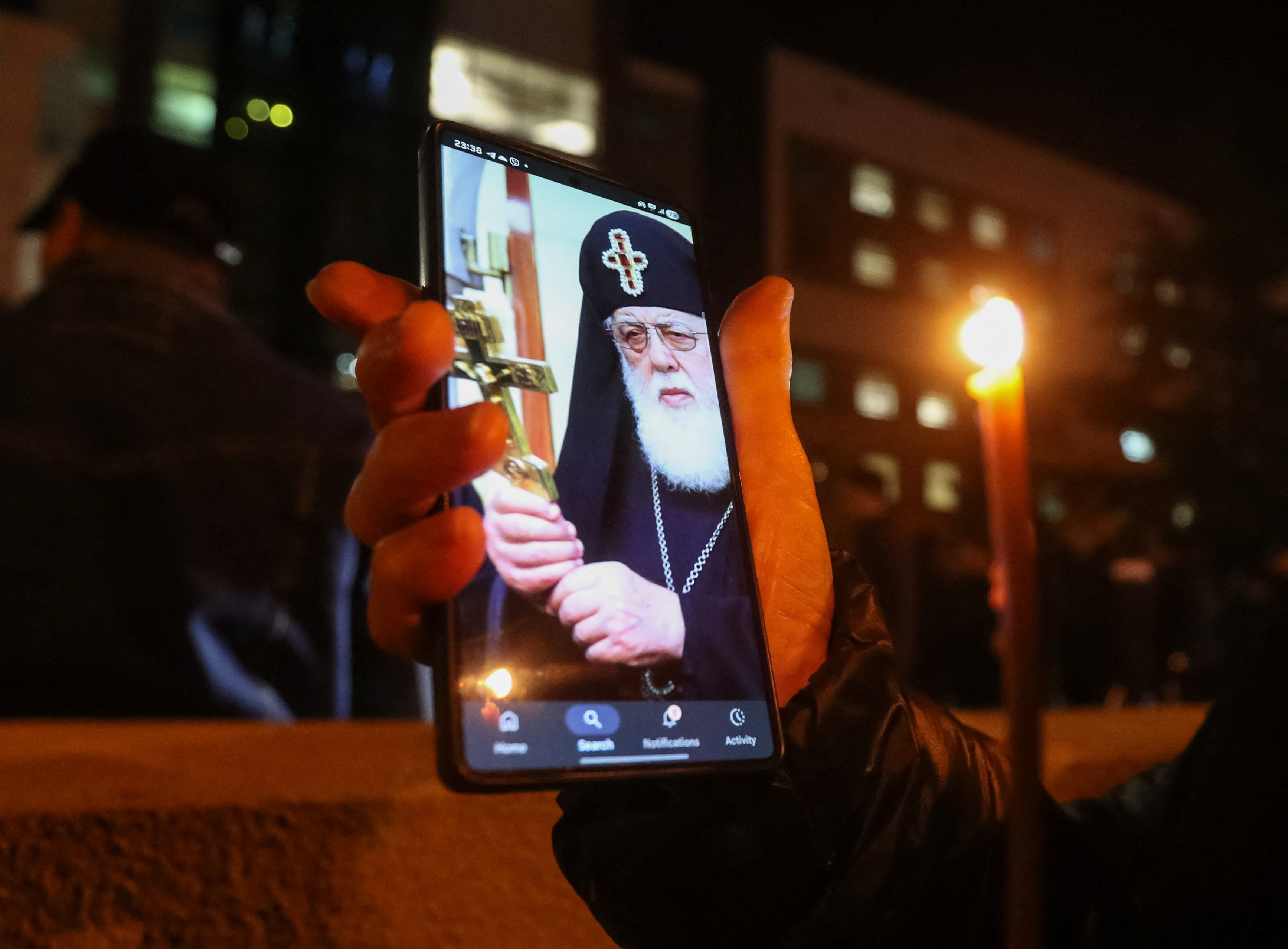A person holds a phone with an image of Georgia's Orthodox Patriarch Ilia II outside the hospital where he was admitted, in Tbilisi