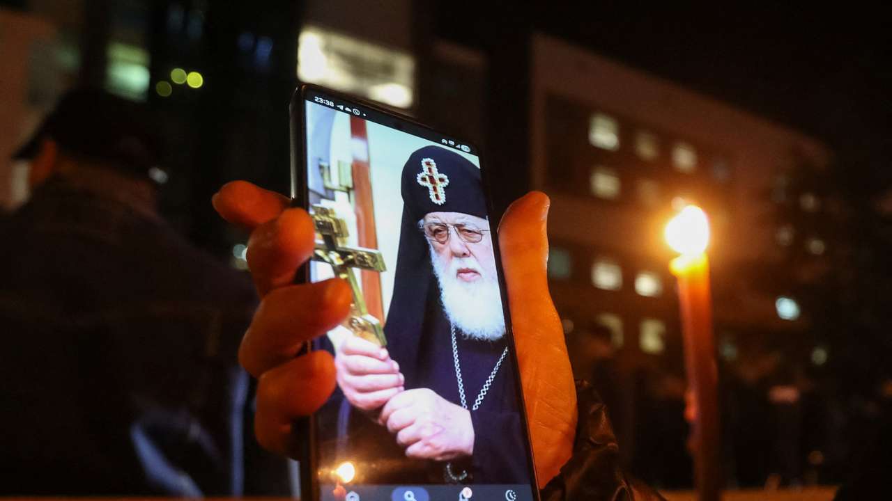 A person holds a phone with an image of Georgia's Orthodox Patriarch Ilia II outside the hospital where he was admitted, in Tbilisi