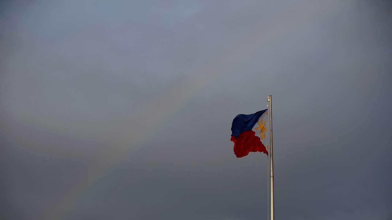 Philippines National Flag is pictured as the rainbow displays over it a day before the annual procession to celebrate Black Nazarene feast day at Quirino Grandstand in Manila