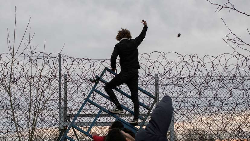 FILE PHOTO: Migrants climb fence at the border as they clash with Greek riot police at Turkey's Pazarkule border crossing with Greece's Kastanies, near Edirne