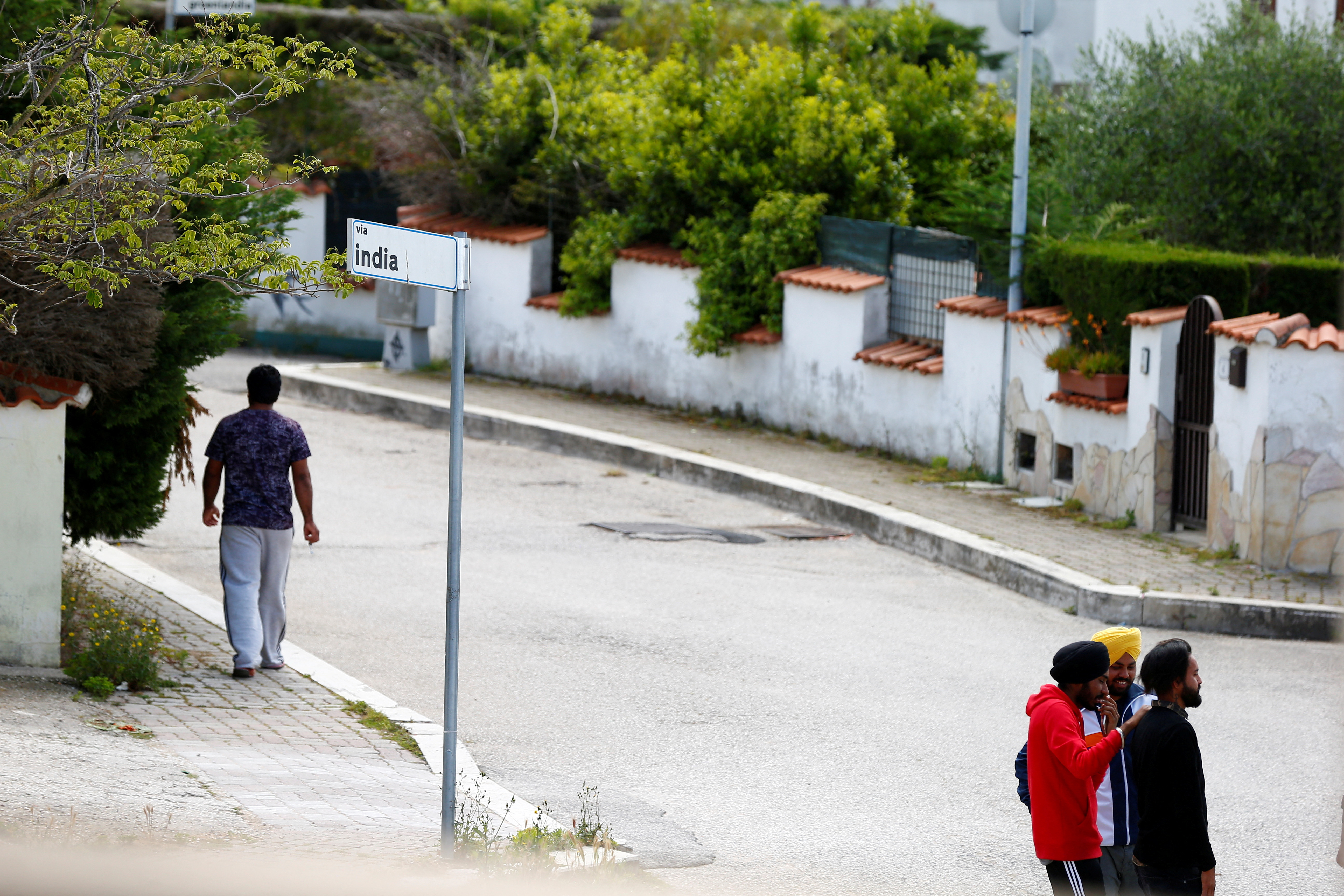 FILE PHOTO: Young Sikh migrant workers walk on a street of Bella Farnia, in the Pontine Marshes, south of Rome