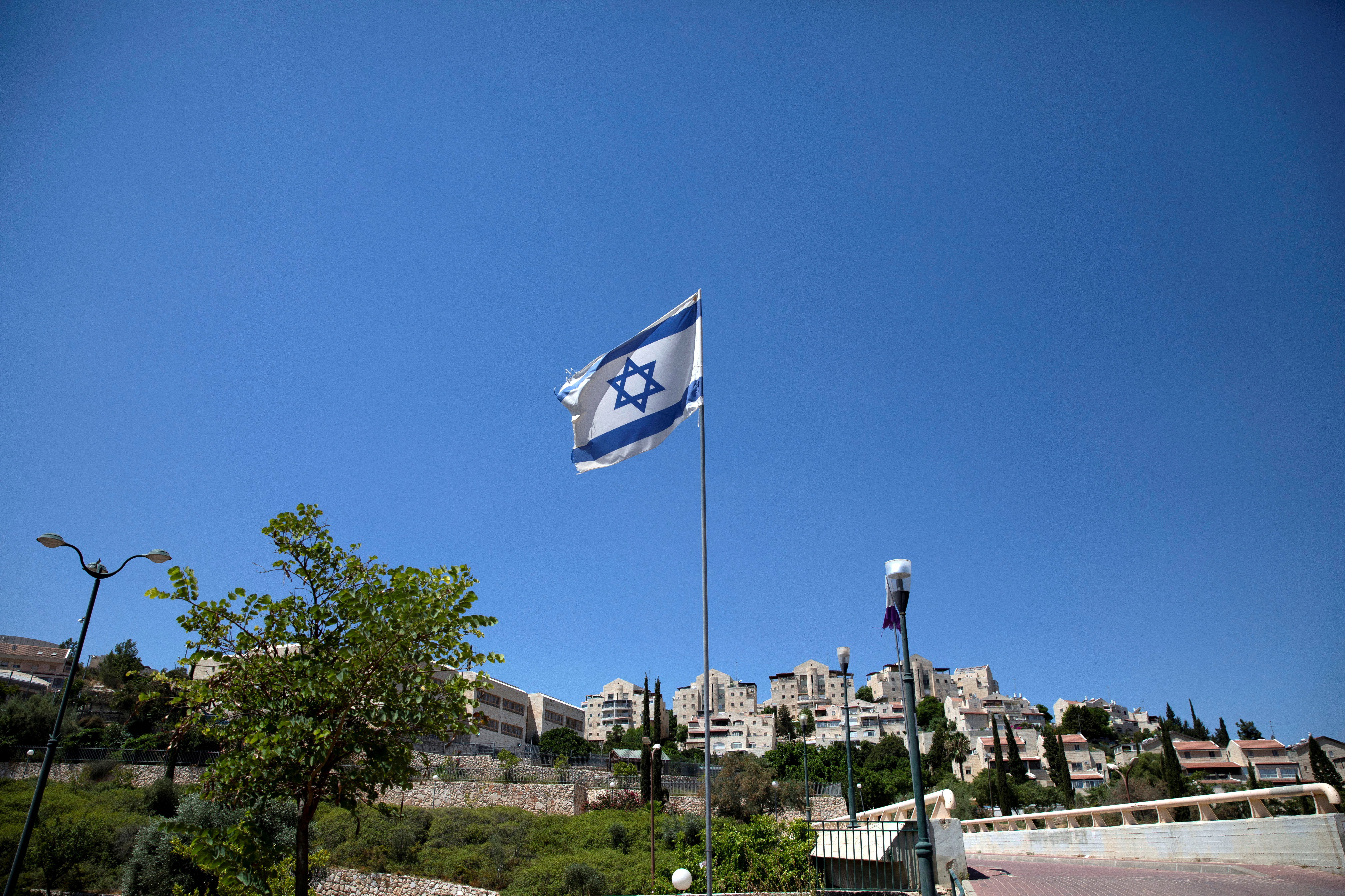 FILE PHOTO: The Israeli national flag flutters as apartments are seen in the background in the Israeli settlement of Maale Adumim in the Israeli-occupied West Bank