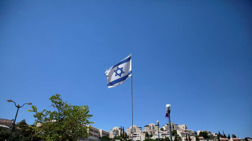 FILE PHOTO: The Israeli national flag flutters as apartments are seen in the background in the Israeli settlement of Maale Adumim in the Israeli-occupied West Bank
