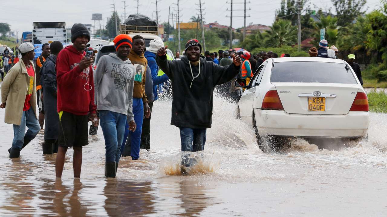 Volunteers direct traffic to clear the Athi River-Namanga highway that was affected after a seasonal river burst its banks following heavy rainfall in Kitengela municipality of Kajiado County