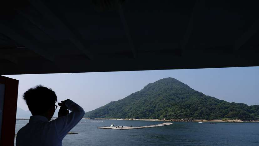 Rebun Kayo takes a photo of Ninoshima Island from a ferry approaching the island, where remains of atomic bomb victims are believed to remain buried since 1945