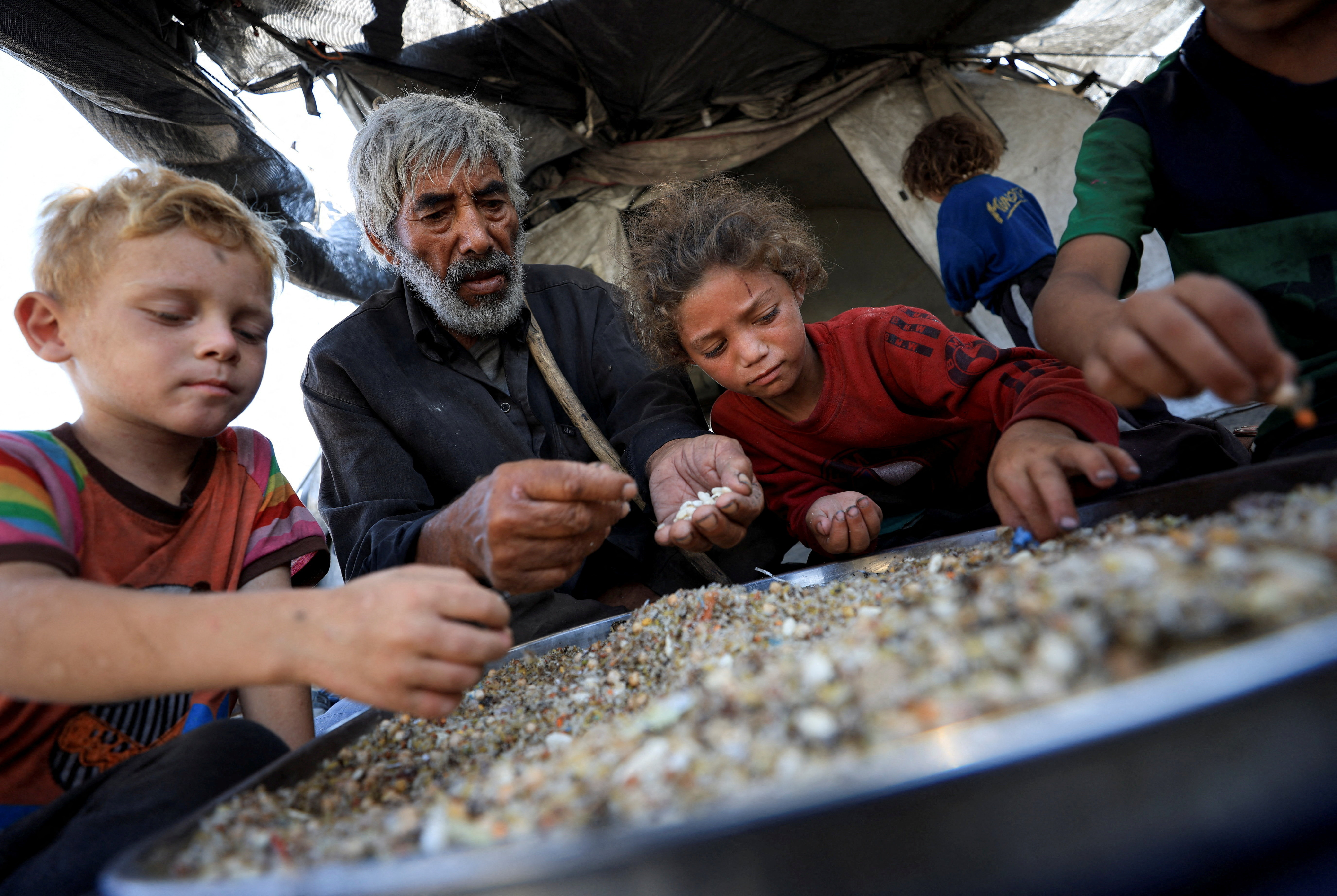 Displaced Palestinians who have not received humanitarian aid survive on leftover food, in Gaza
