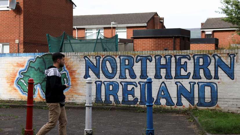 Man walks past a mural that says ‘Northern Ireland’, on Sandy Row in Belfast