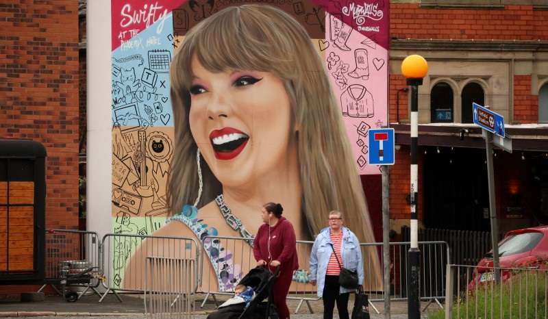 People walk past a mural by Murwalls of U.S. musician Taylor Swift outside the Phoenix Hotel, in Liverpool