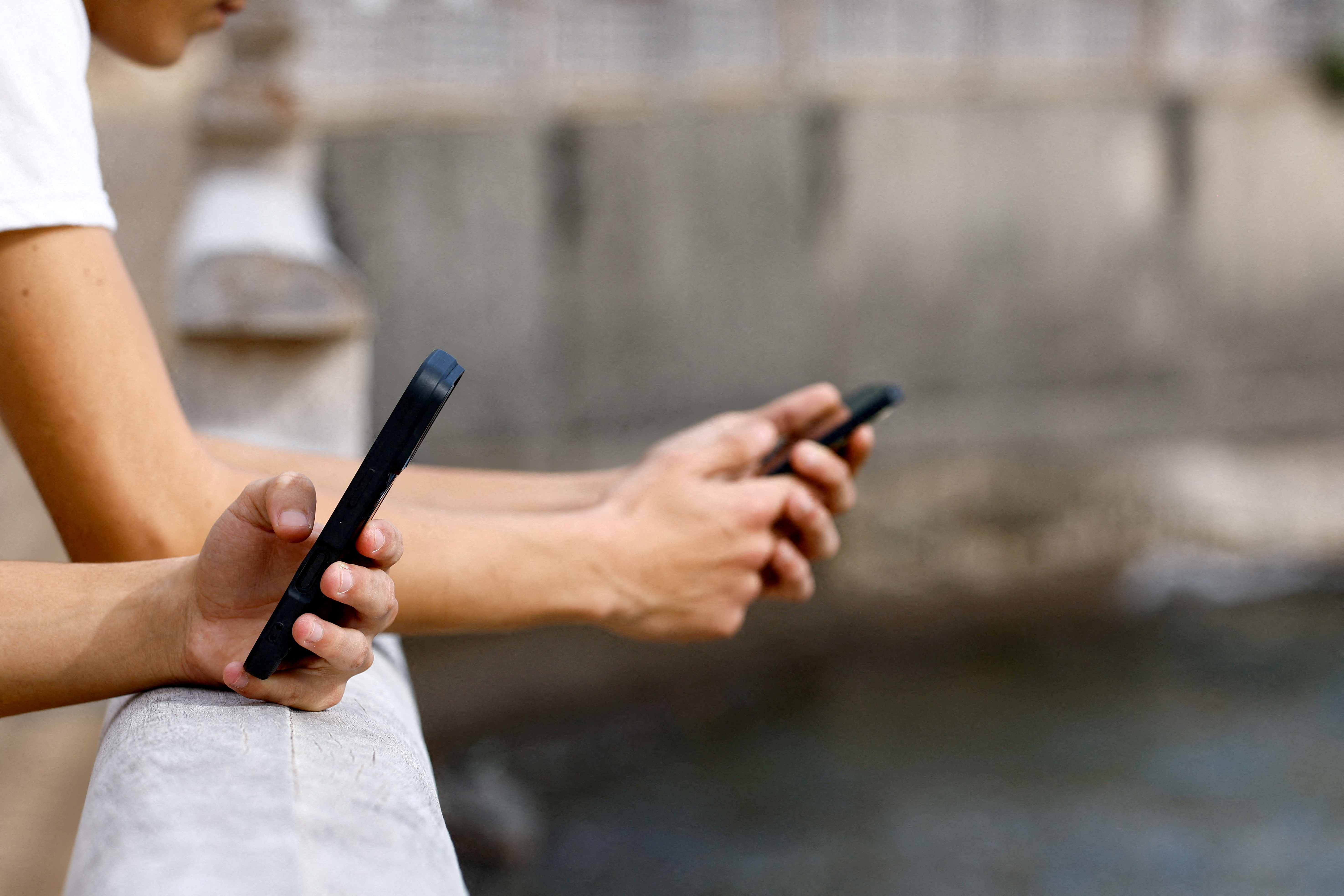 FILE PHOTO: Two 15-year-olds use social media on their mobile phones in Arinaga, on the island of Gran Canaria
