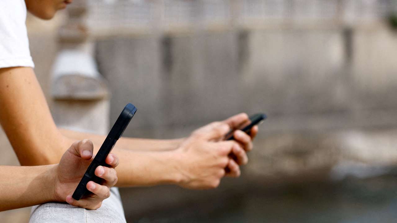 FILE PHOTO: Two 15-year-olds use social media on their mobile phones in Arinaga, on the island of Gran Canaria