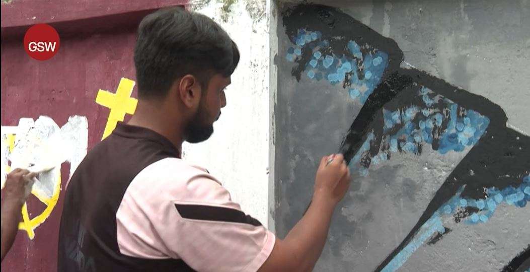 A student paints a wall in the capital of Bangladesh, Dhaka