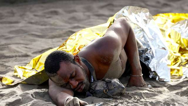 FILE PHOTO: A migrant rests on the sand after arriving in a fiber boat at Las Burras beach in San Agustin