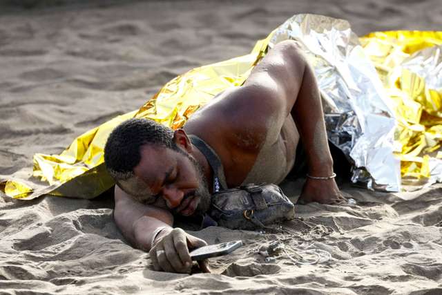 FILE PHOTO: A migrant rests on the sand after arriving in a fiber boat at Las Burras beach in San Agustin
