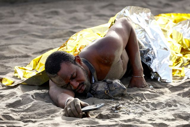 FILE PHOTO: A migrant rests on the sand after arriving in a fiber boat at Las Burras beach in San Agustin