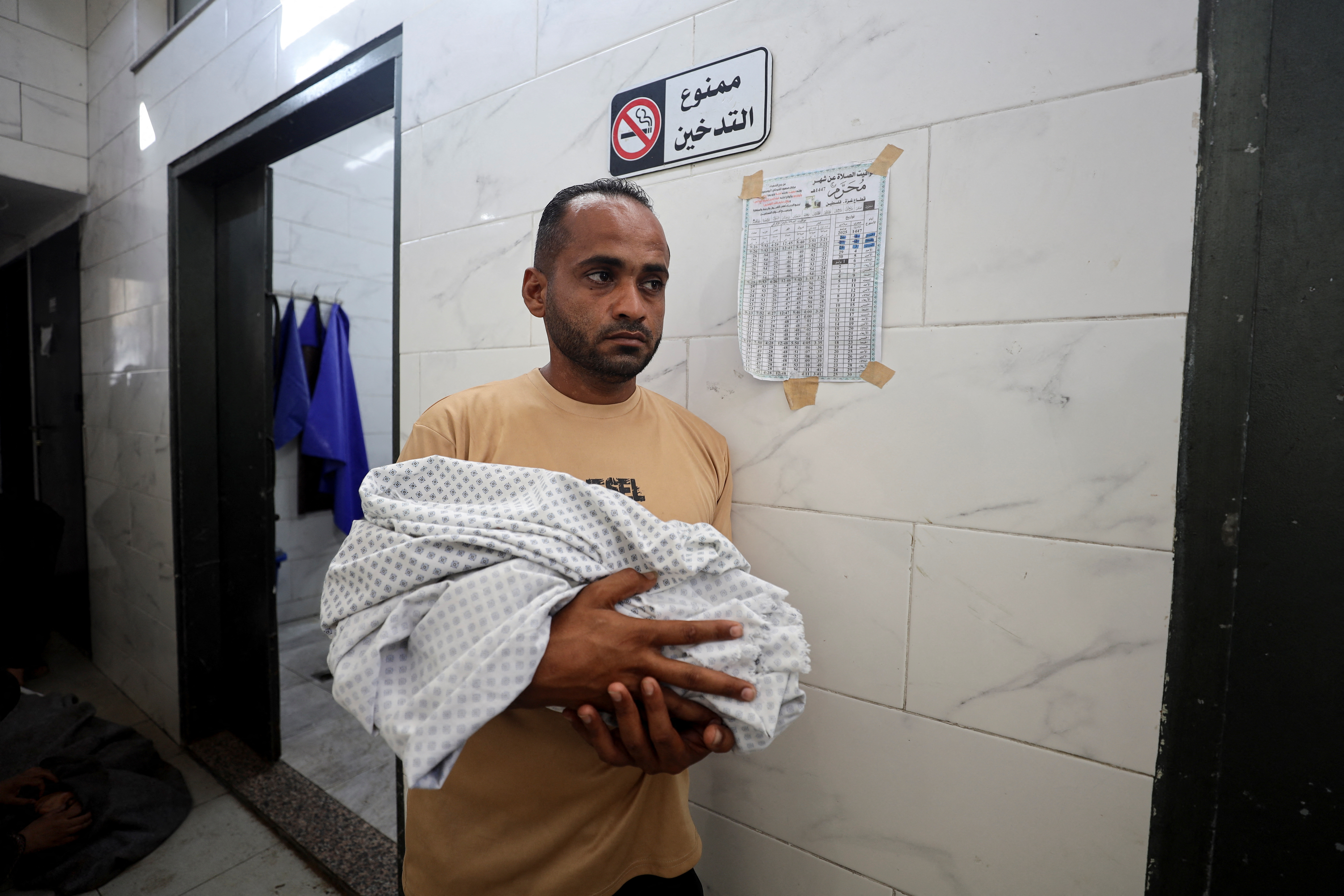 Adham carries the body of his nephew, six-week-old infant Yousef al-Safadi, who died of starvation according to health officials, in Gaza City