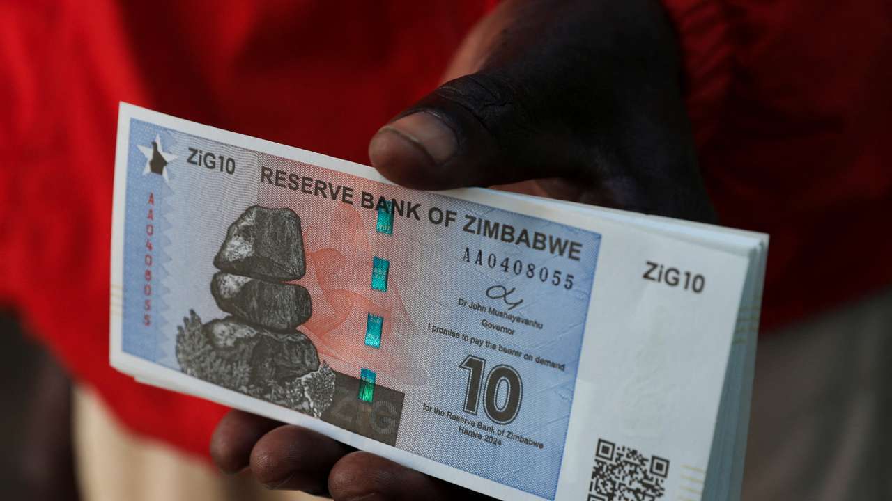 A man shows new Zimbabwe gold-backed currency after withdrawing from a local bank in Harare