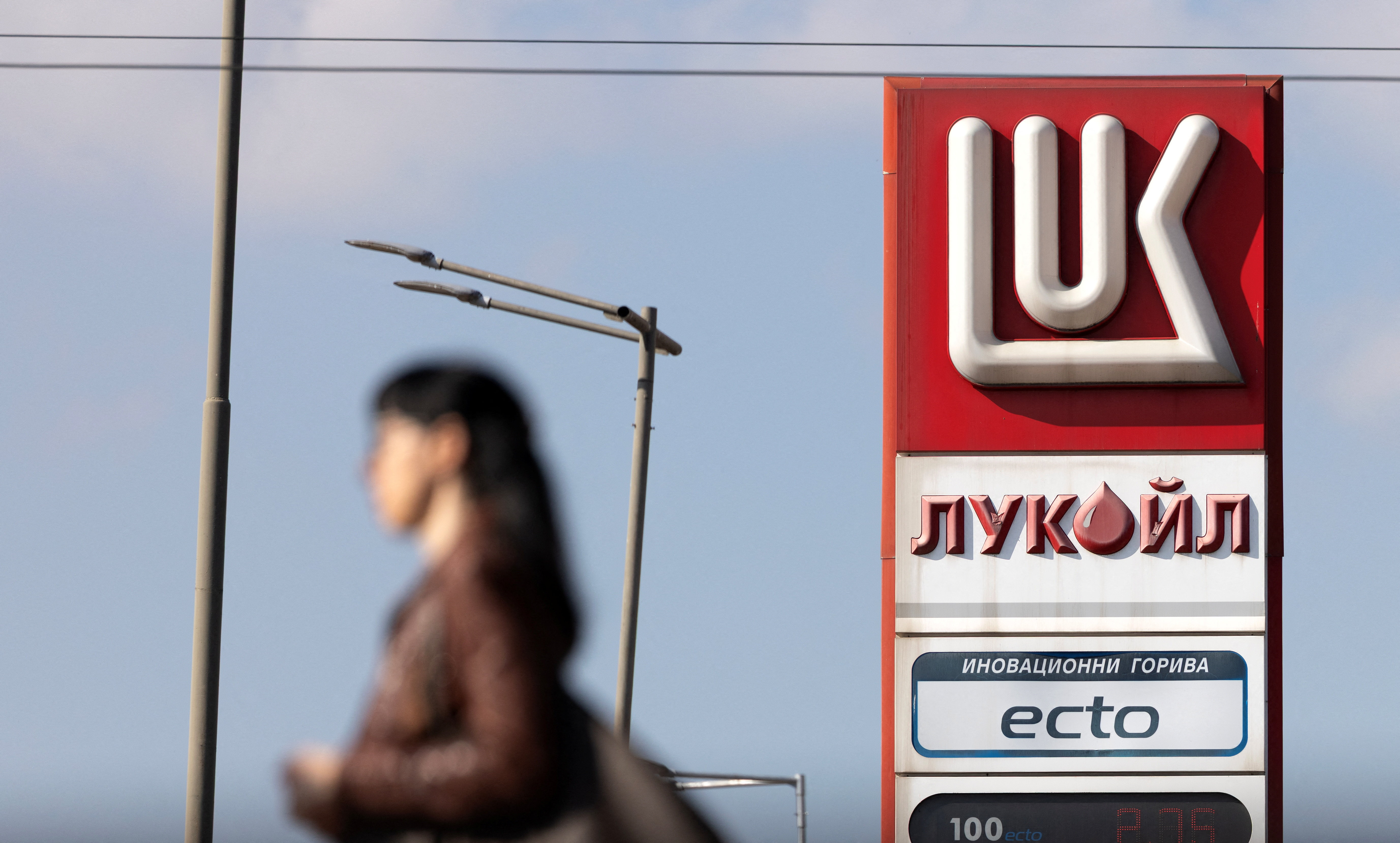 Woman walks near a Lukoil gas station in Sofia
