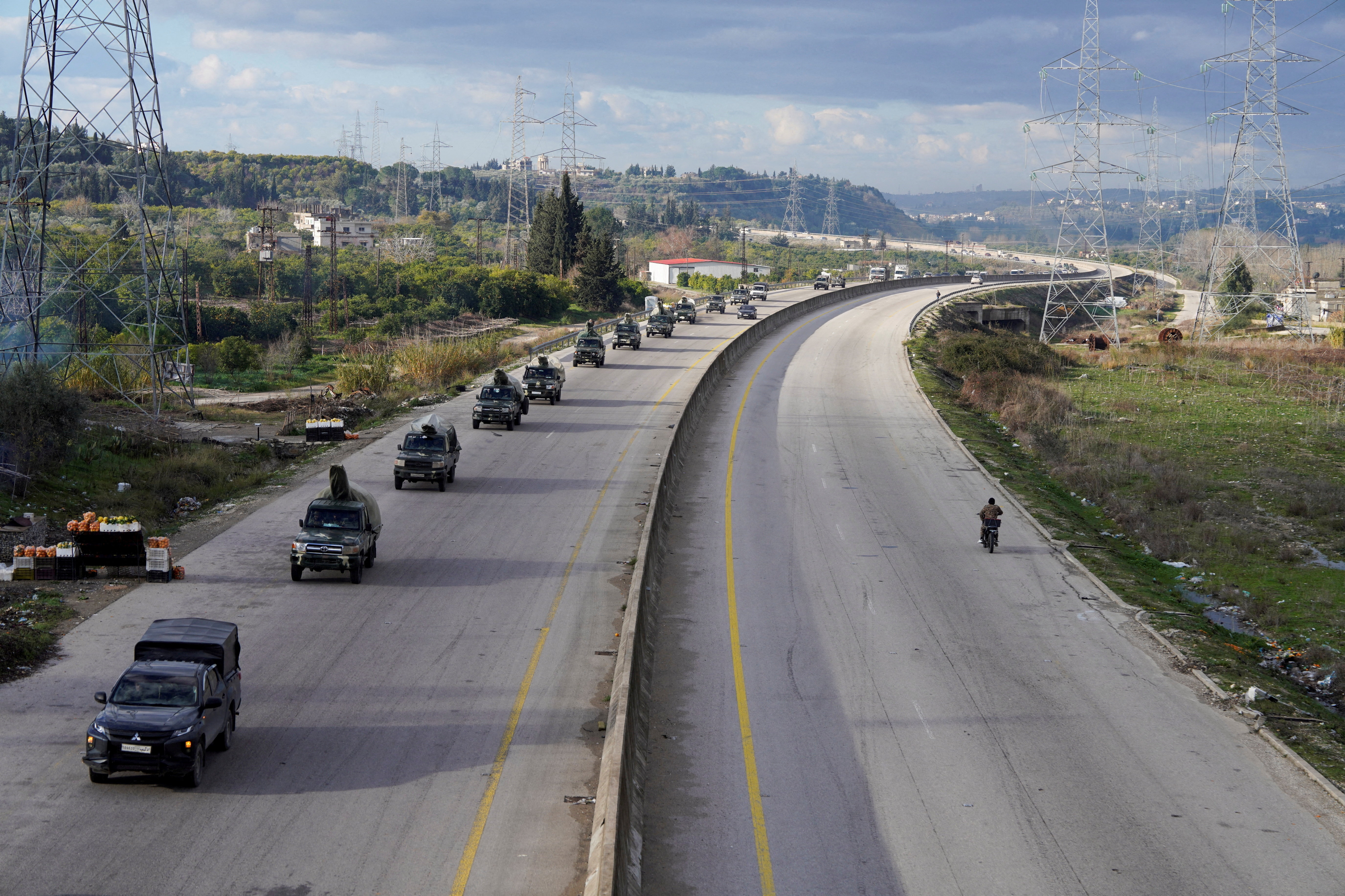 Military vehicles drive along a road in Latakia
