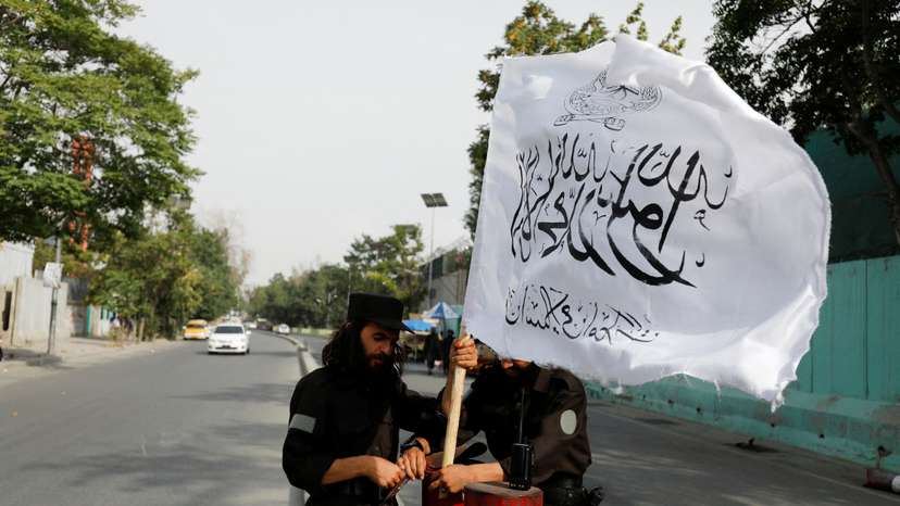 FILE PHOTO: Taliban fighters install a Taliban flag on a checkpoint in Kabul