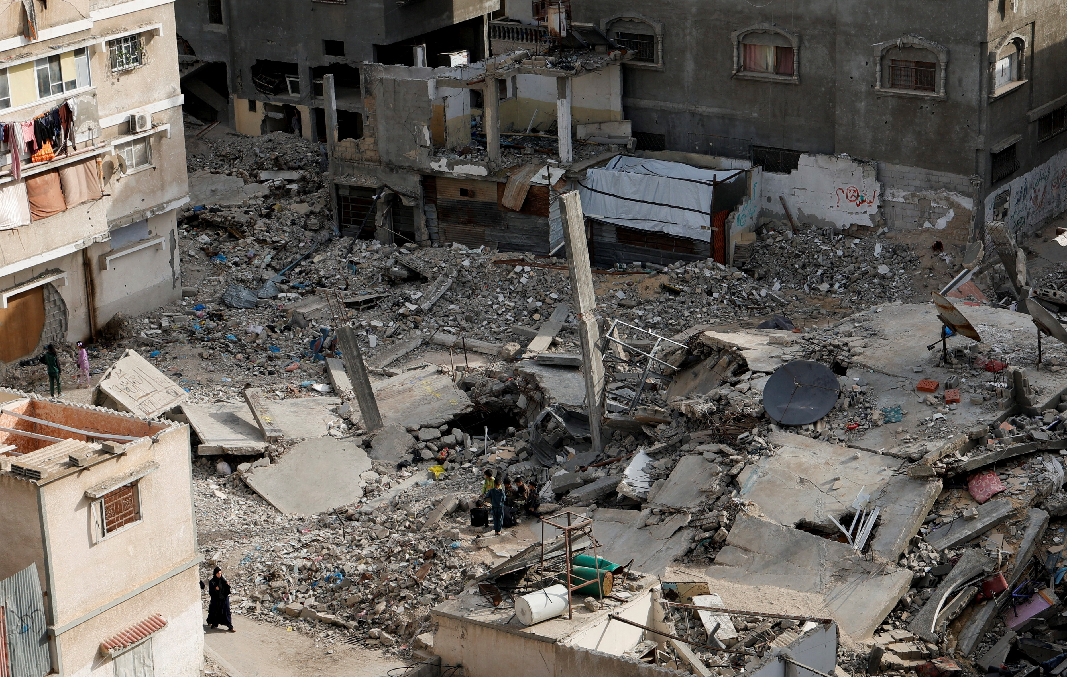 A Palestinian woman walks near the rubble of houses, in Khan Younis