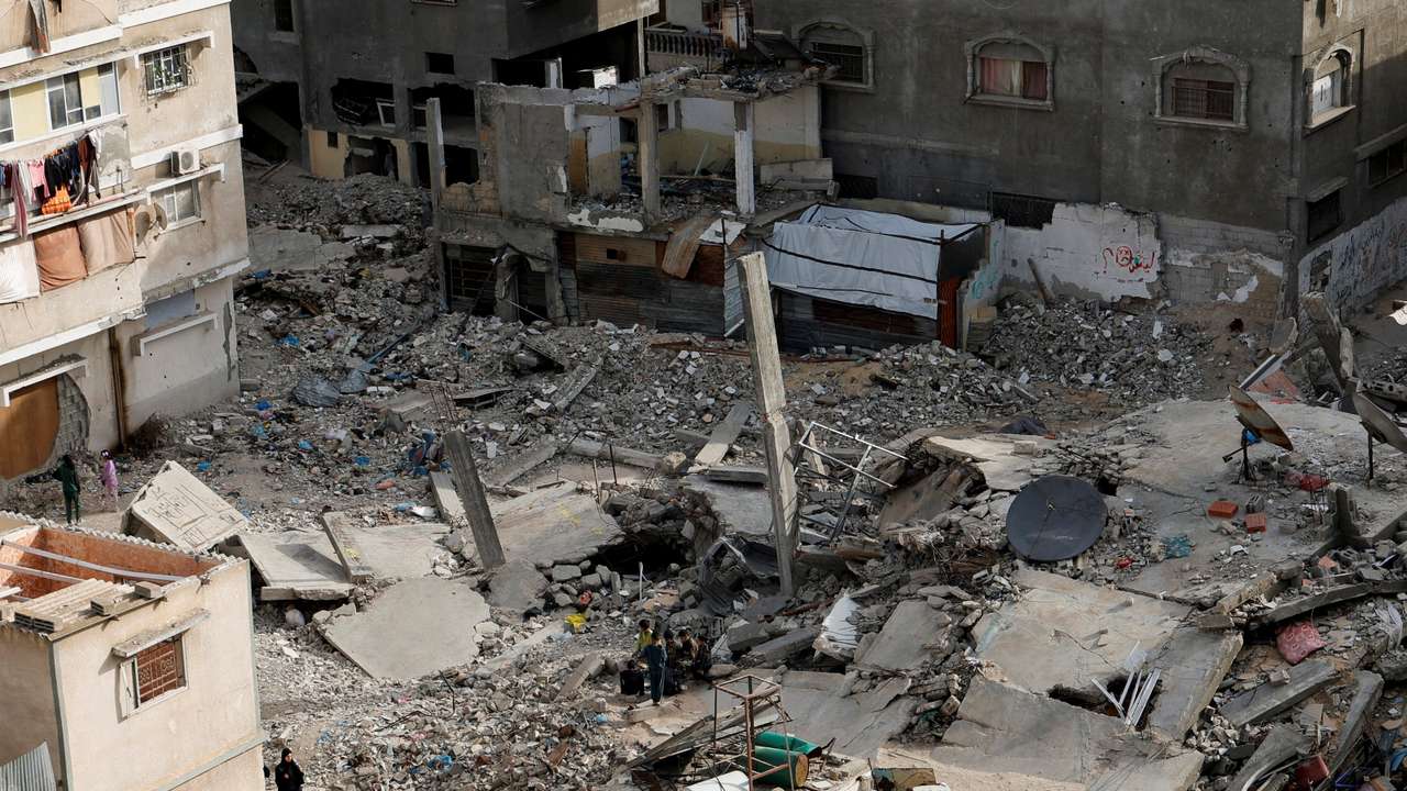 A Palestinian woman walks near the rubble of houses, in Khan Younis