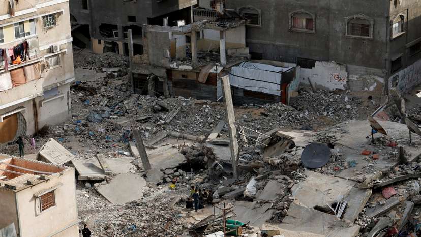 A Palestinian woman walks near the rubble of houses, in Khan Younis