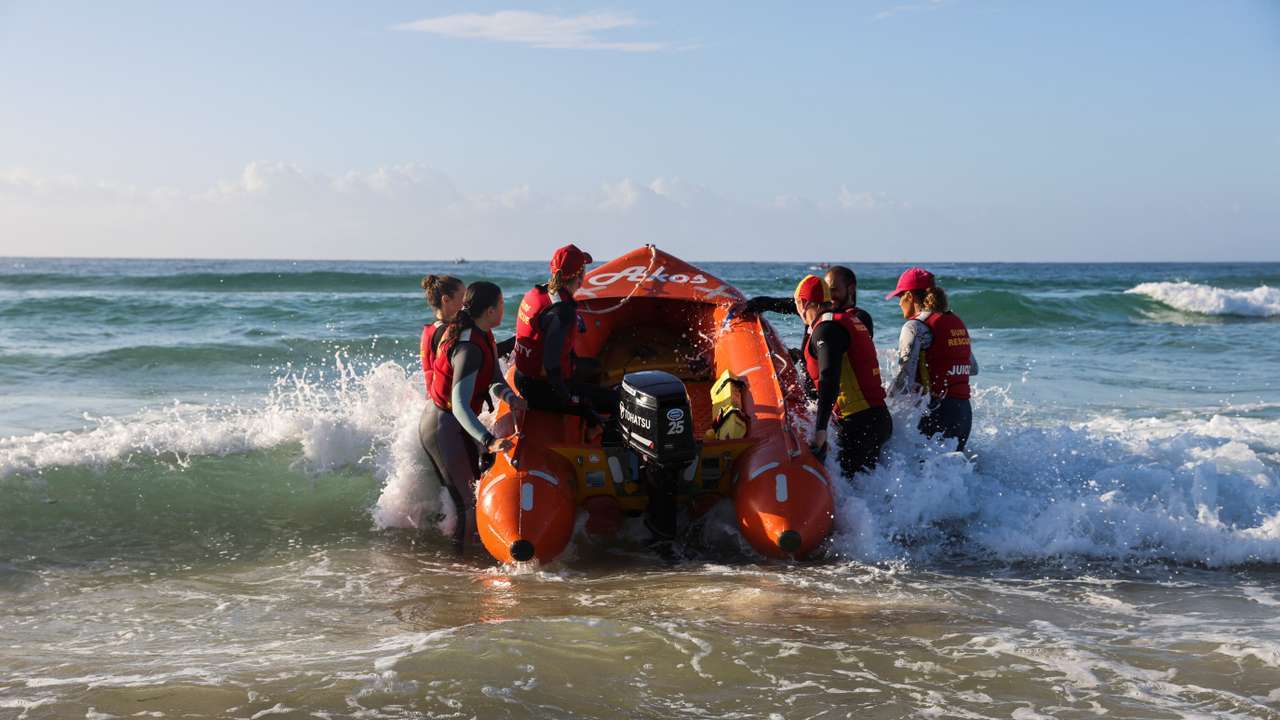 IRB Racing team carries a boat into the ocean on Bondi Beach