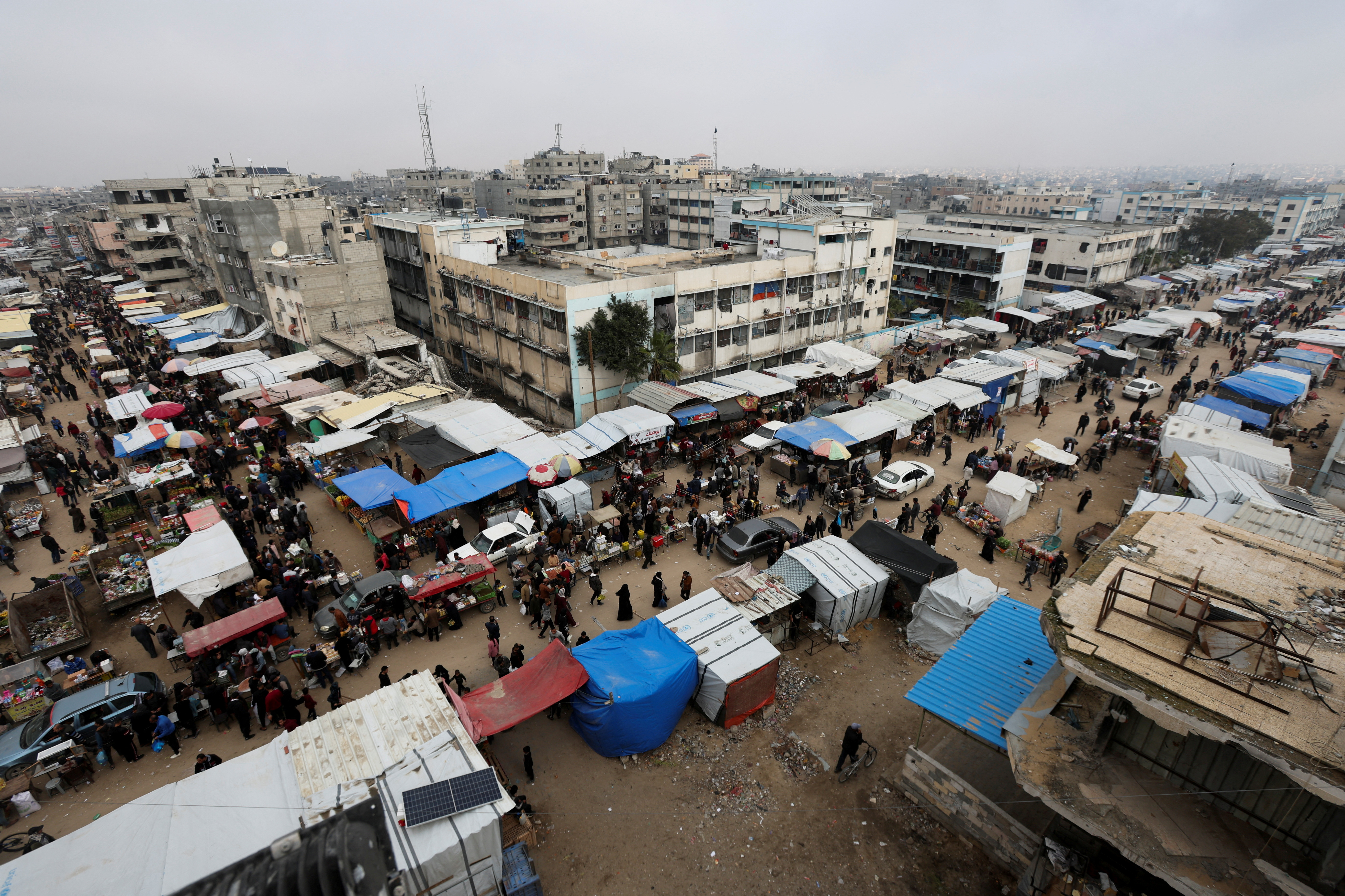 Palestinians walk at a street market amid ceasefire negotiations, in Khan Younis in the southern Gaza Strip