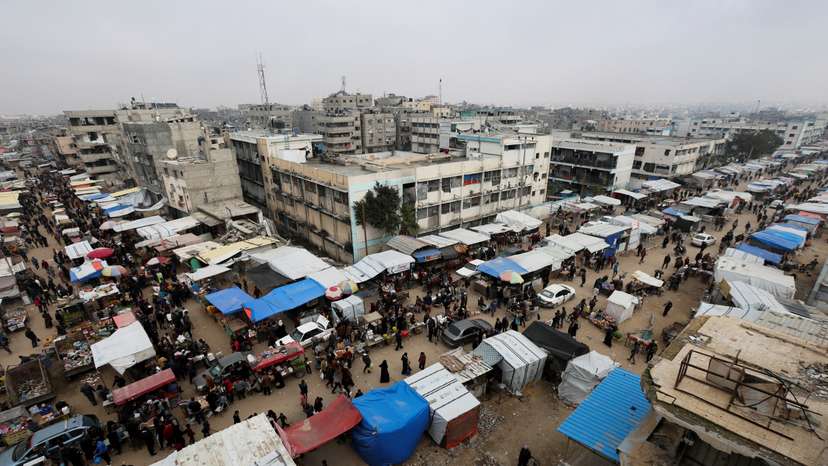 Palestinians walk at a street market amid ceasefire negotiations, in Khan Younis in the southern Gaza Strip