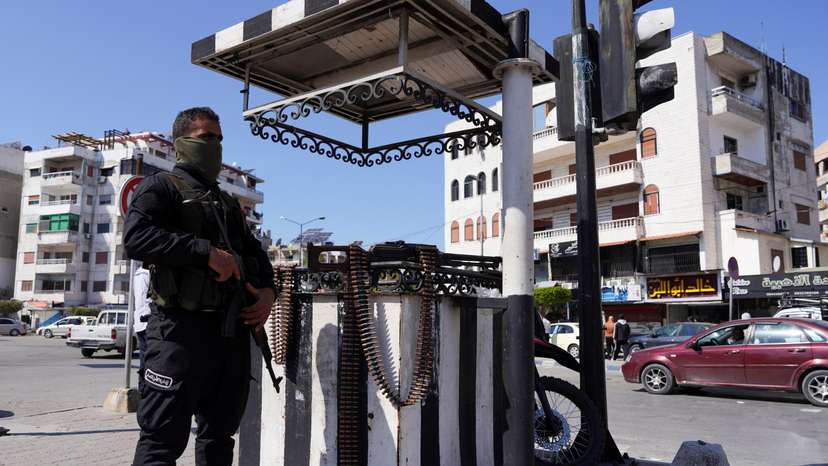A member of the Syrian security forces stands guard along a street, in Latakia