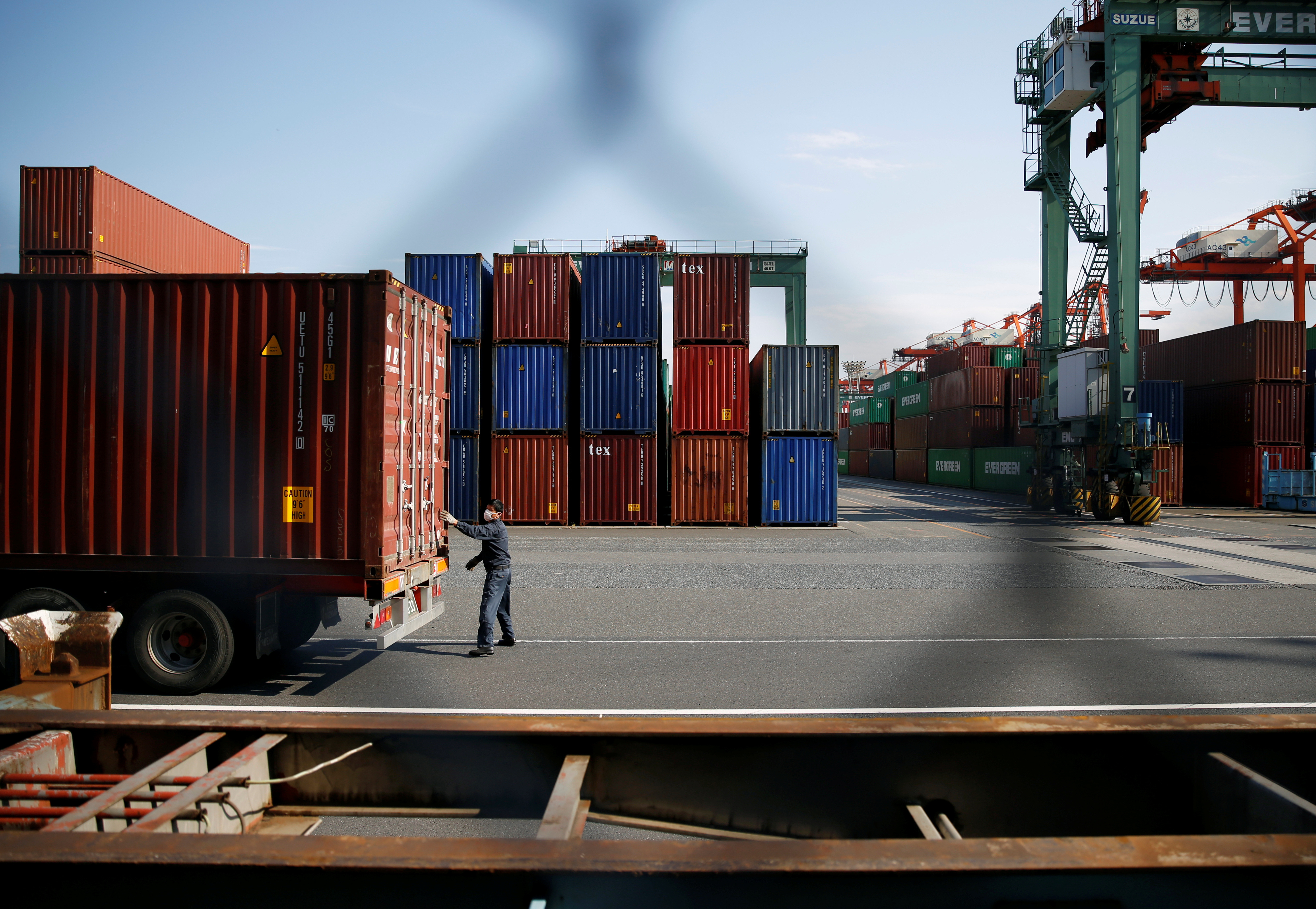 A man works between shipping containers at a port in Tokyo, Japan