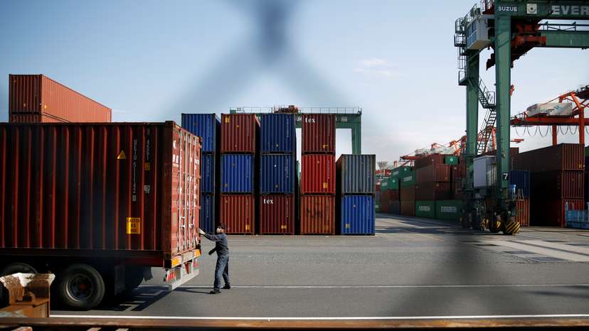A man works between shipping containers at a port in Tokyo, Japan