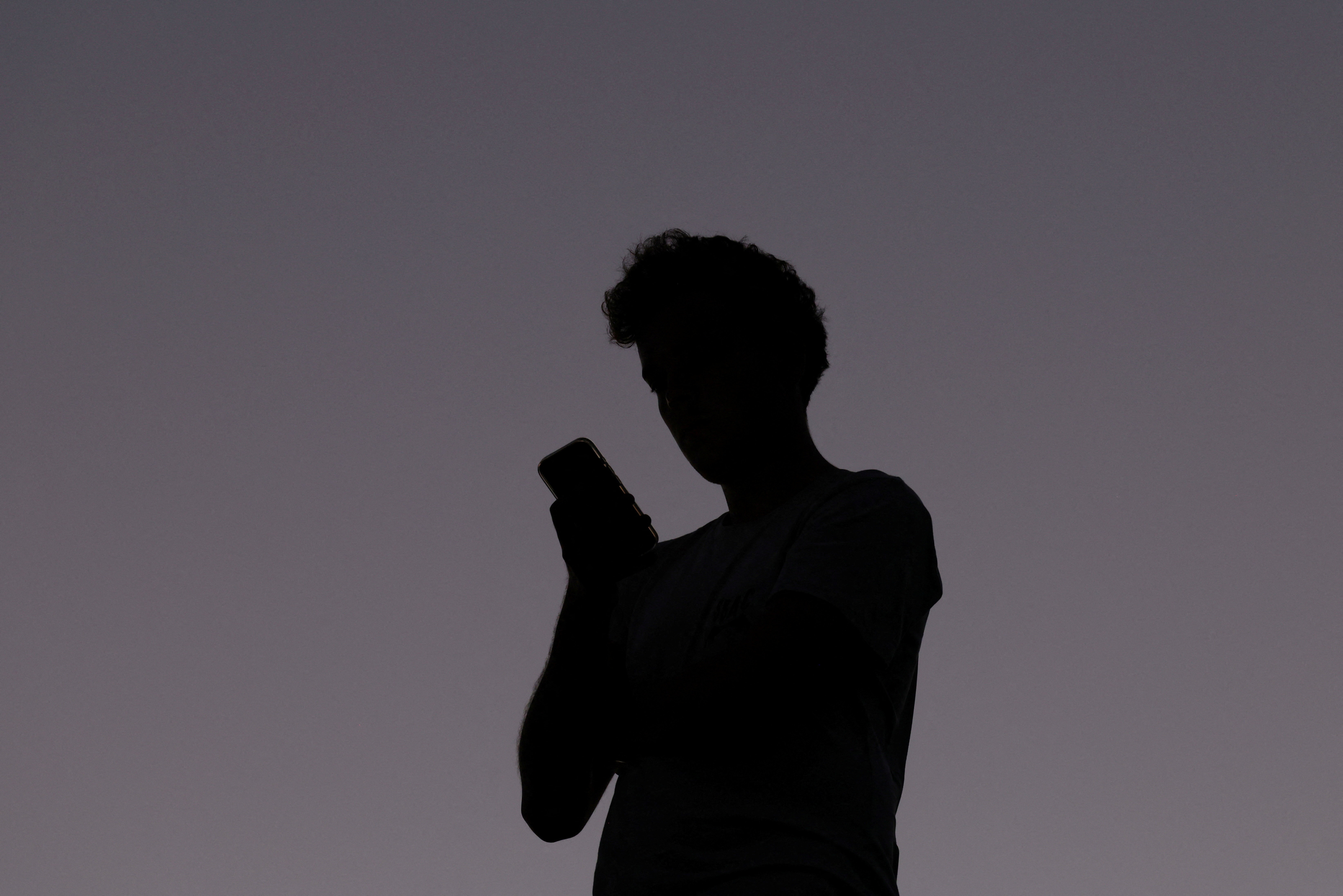 A man uses a mobile phone at dusk in Brisbane