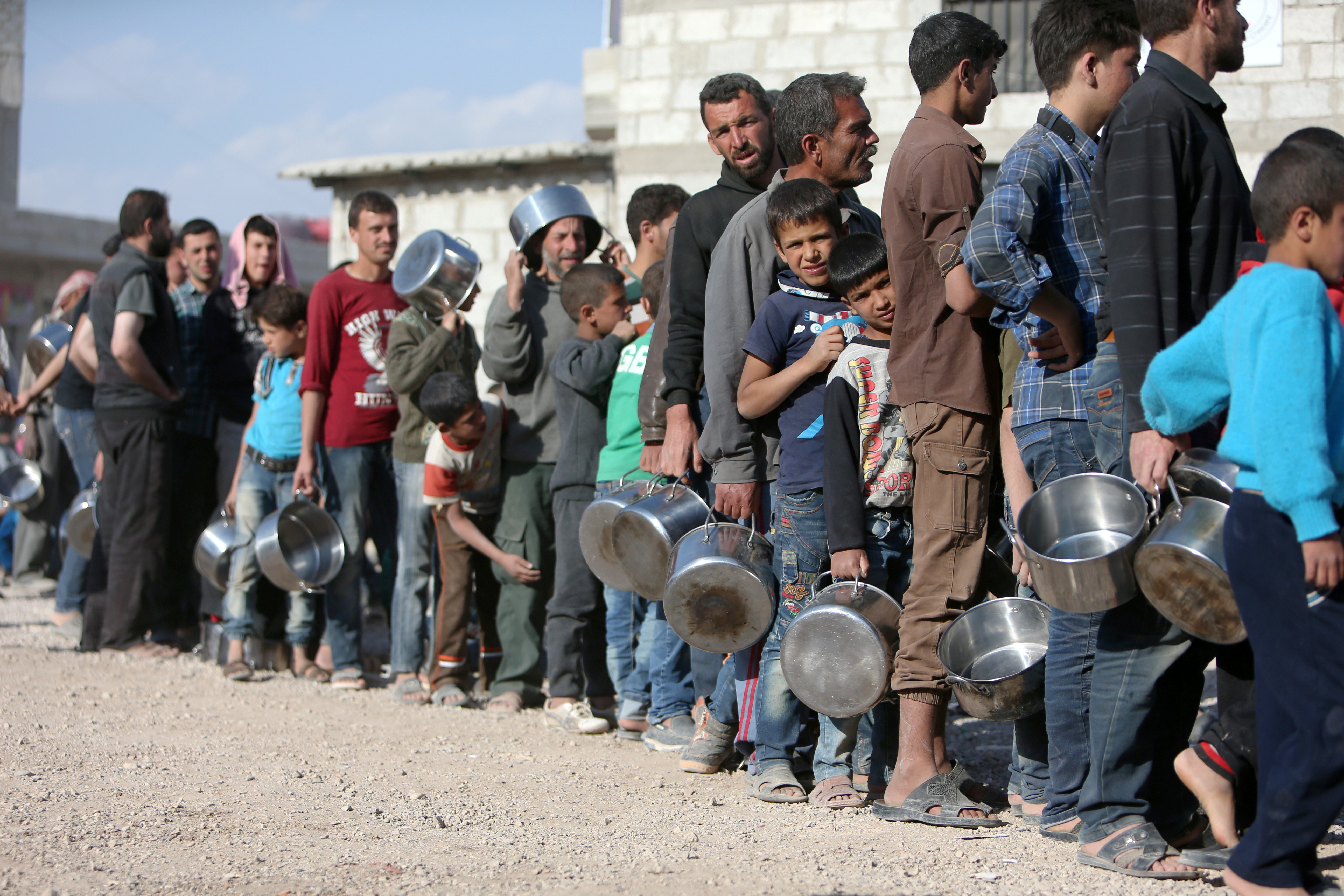 Internally displaced Syrians from eastern Ghouta queue for food in Herjelleh shelter in Damascus countryside
