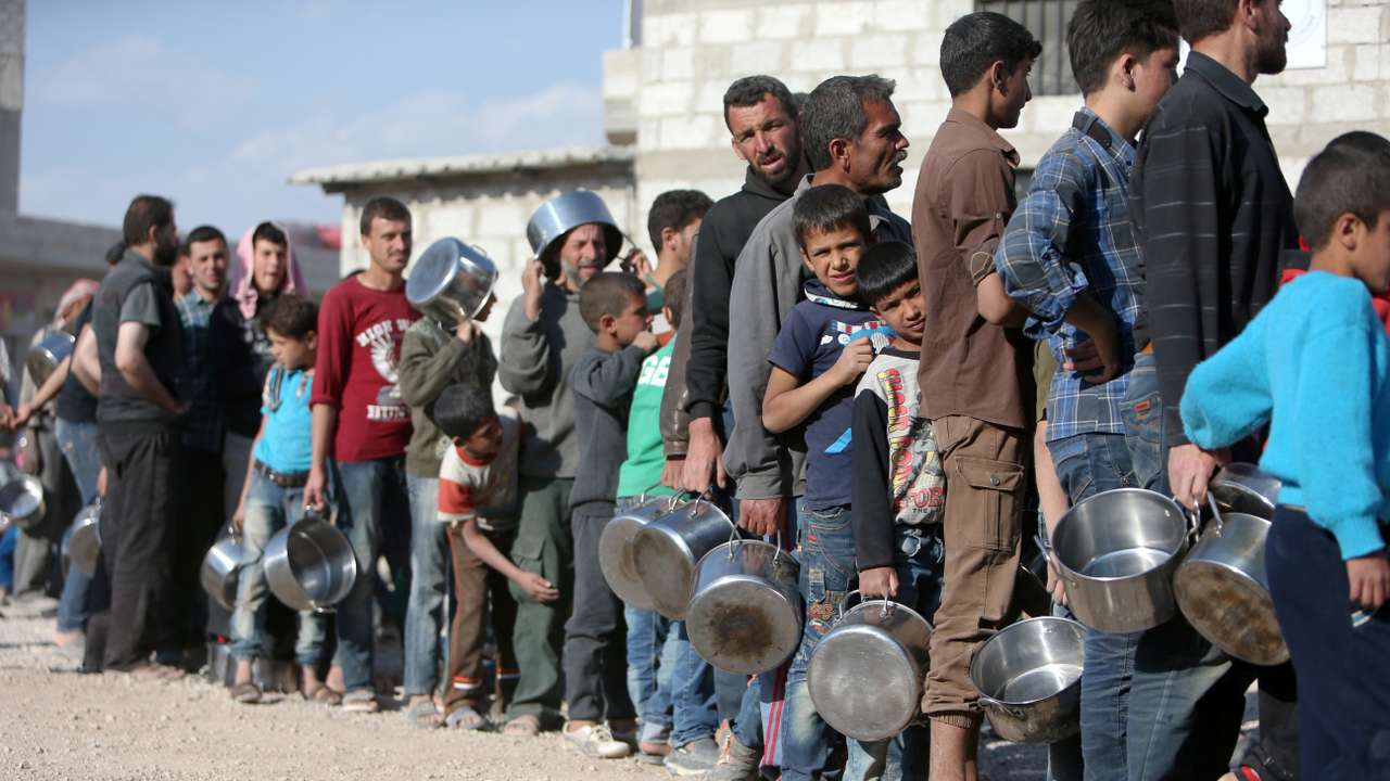 Internally displaced Syrians from eastern Ghouta queue for food in Herjelleh shelter in Damascus countryside