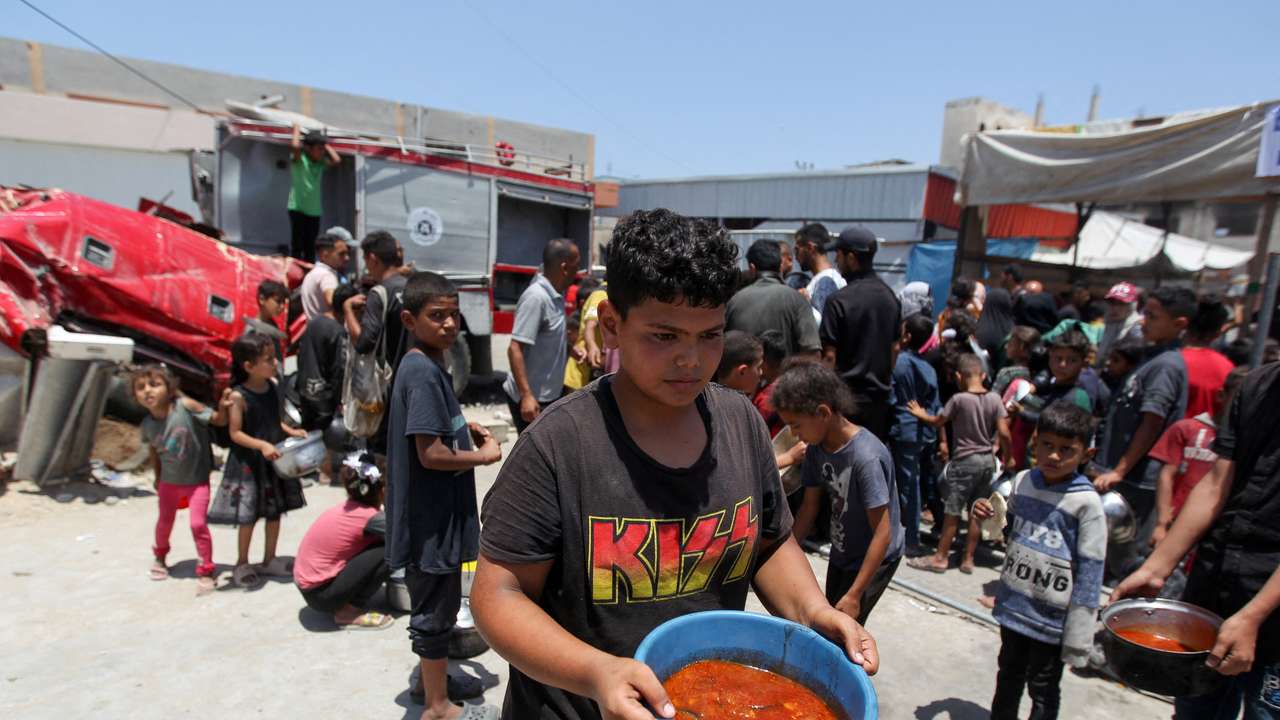 FILE PHOTO: Palestinians gather to receive food cooked by a charity kitchen, in Khan Younis