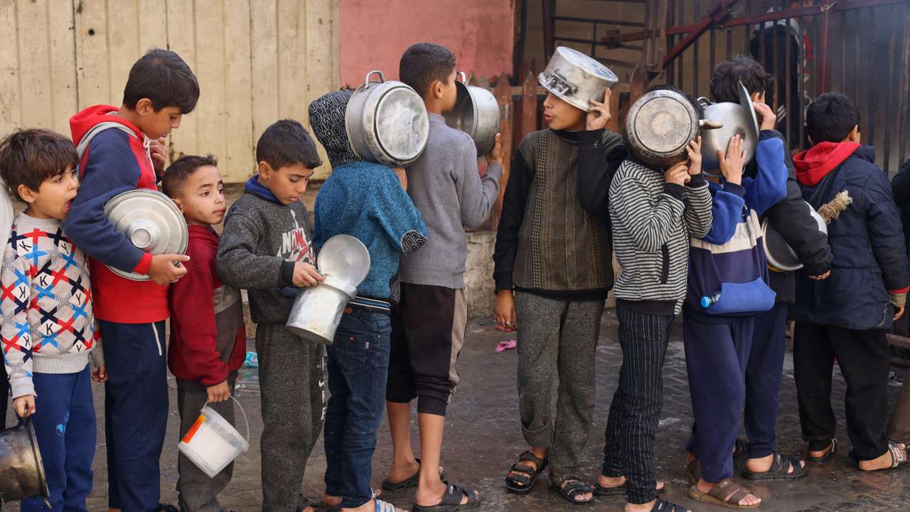 Palestinian children wait to receive food cooked by a charity kitchen, in Rafah