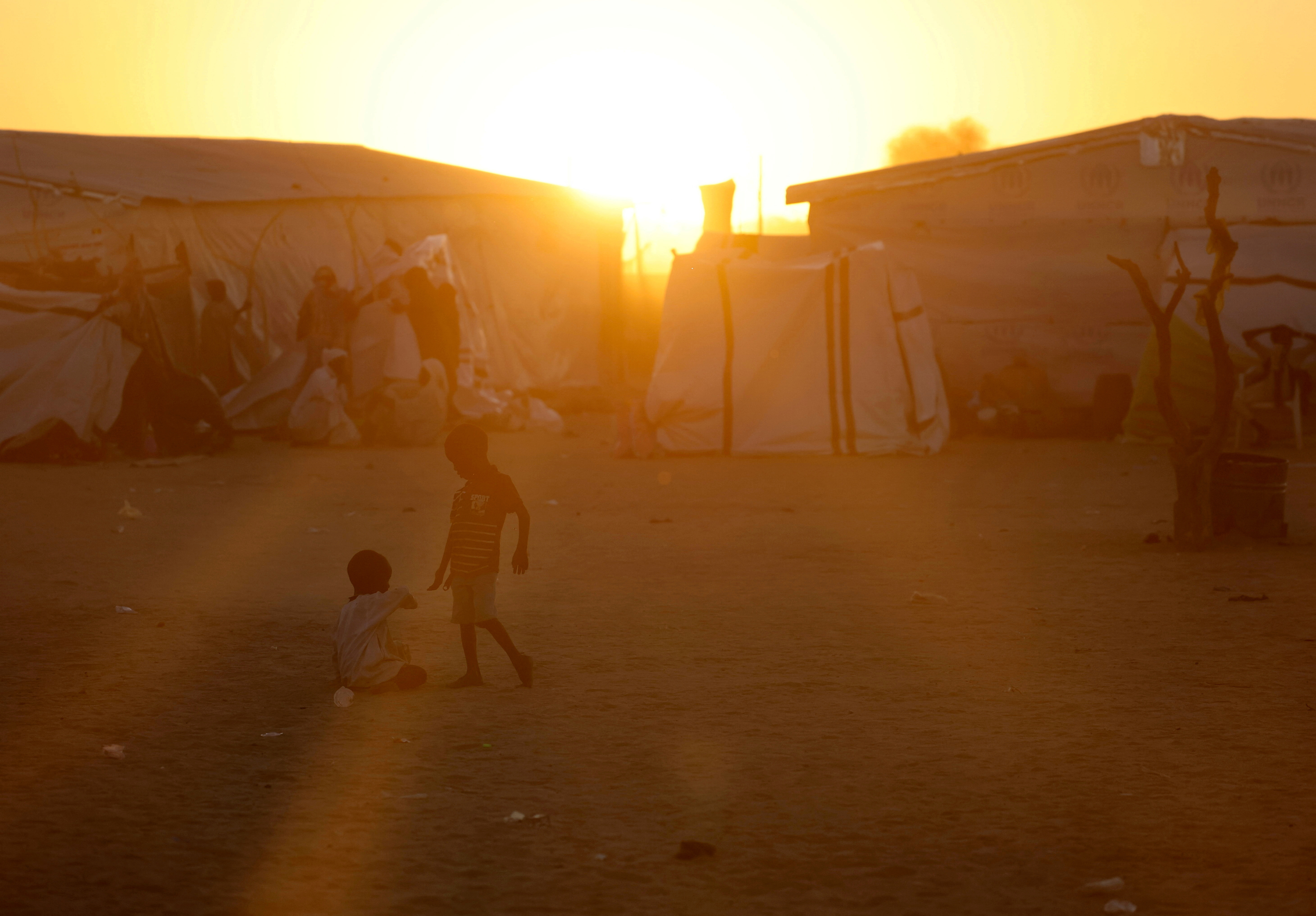 Sudanese refugee children from al-Fashir play during the sunset over the Tine transit refugee camp