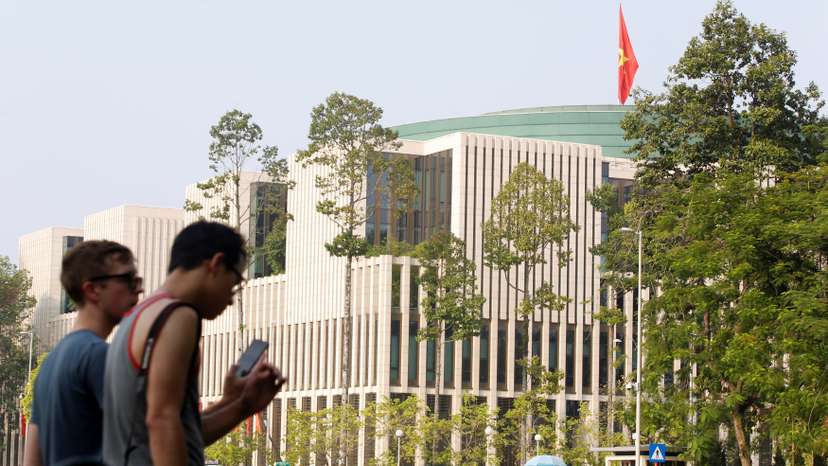 Tourists walk past Vietnam's National Assembly (Parliament) building in Hanoi, Vietnam
