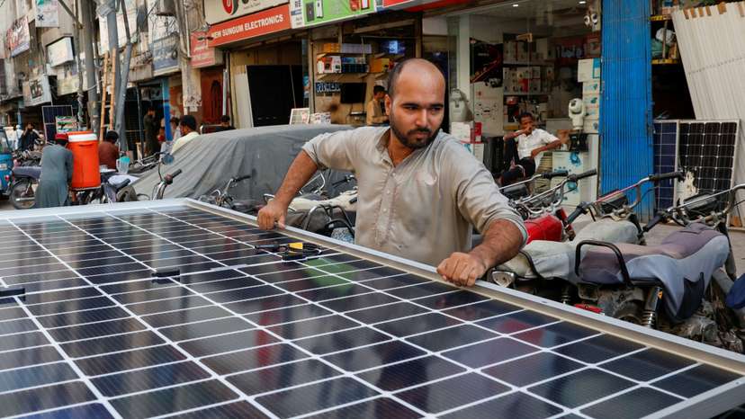 A worker loads solar panels on a vehicle outside a shop in Karachi