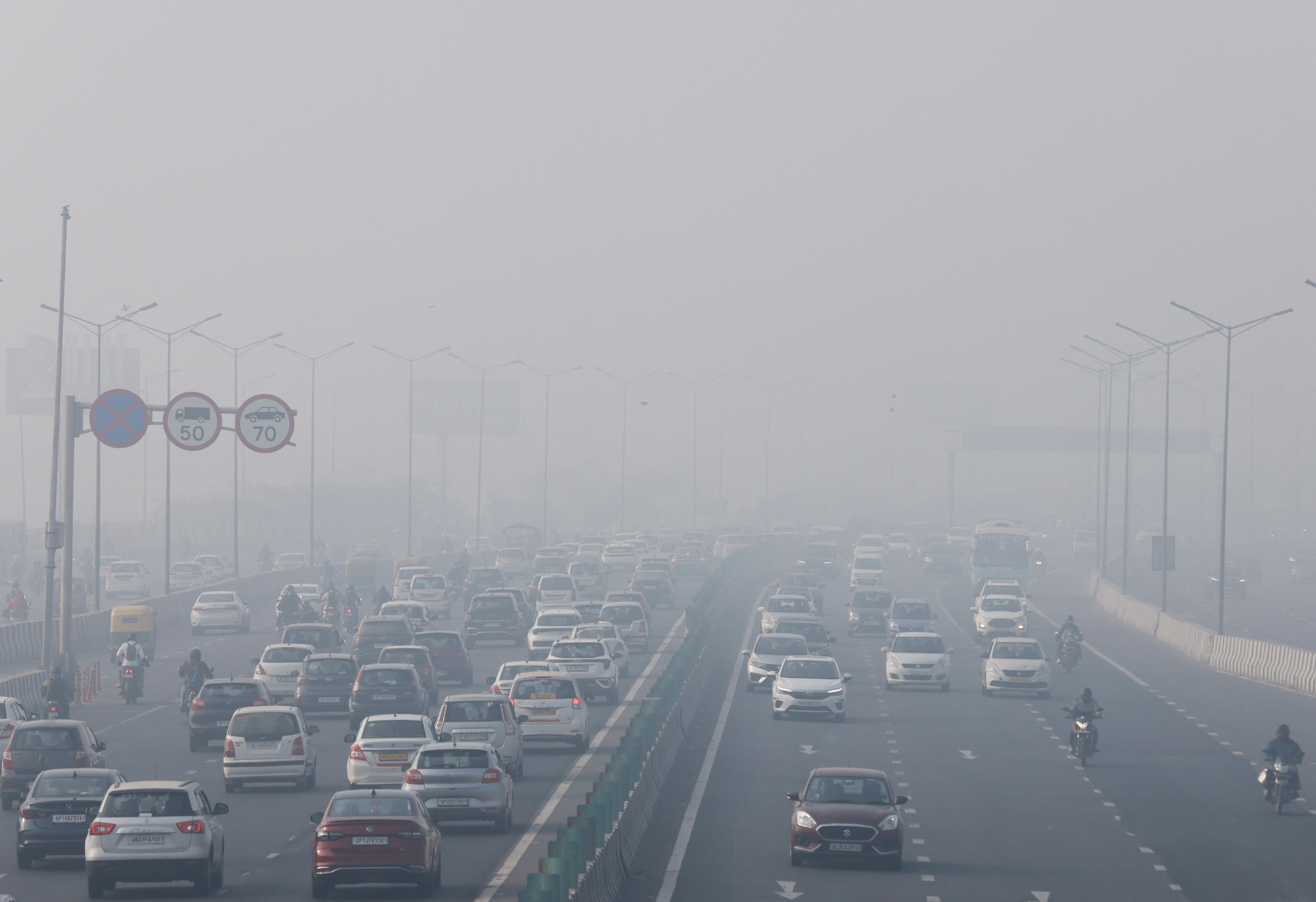 Traffic moves along a highway shrouded in heavy smog in New Delhi