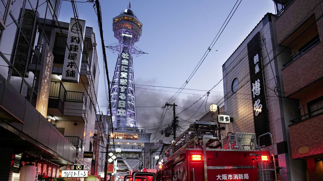 Smoke rises from a fire site at a commercial building near a famous tourist landmark Tsutenkaku Tower, in Osaka