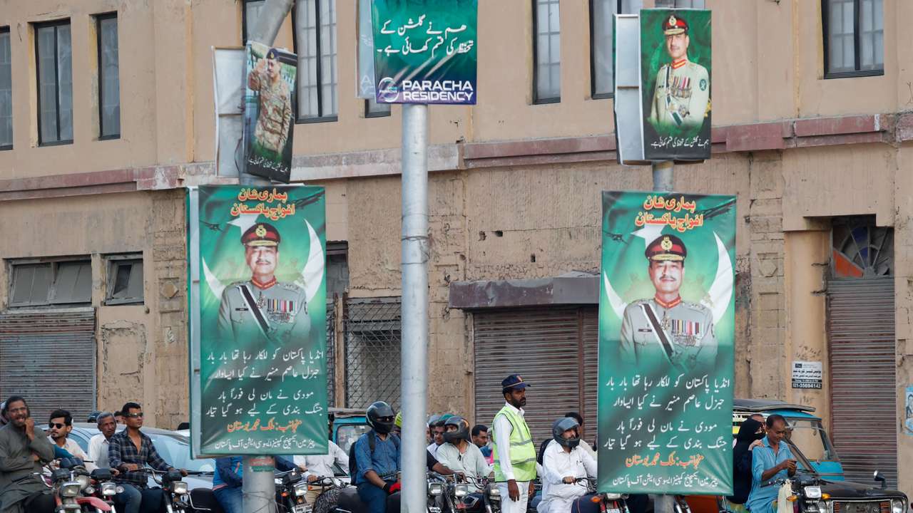 A police officer stands in front of the traffic, next to posters of the Chief of Army Staff of Pakistan Asim Munir, in Karachi