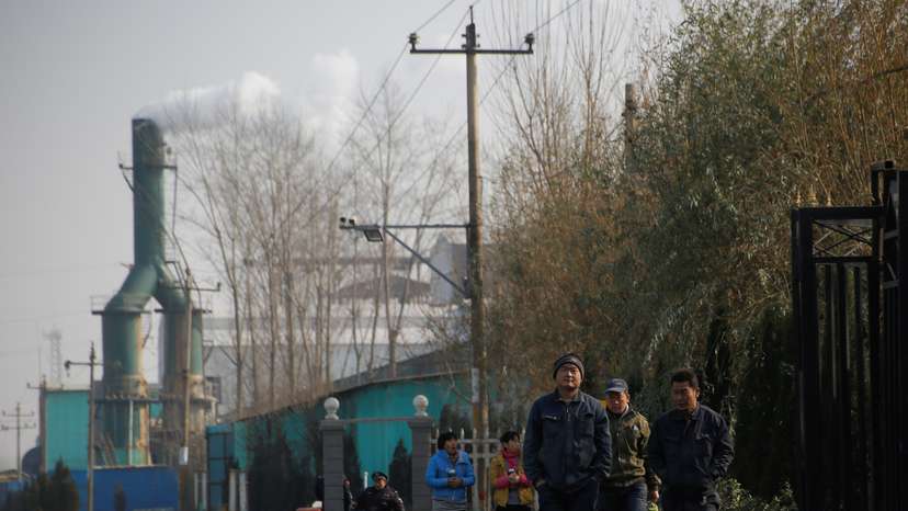 Smoke billows from a chimney as workers leave a factory in rural Gaoyi county near Shijiazhuang