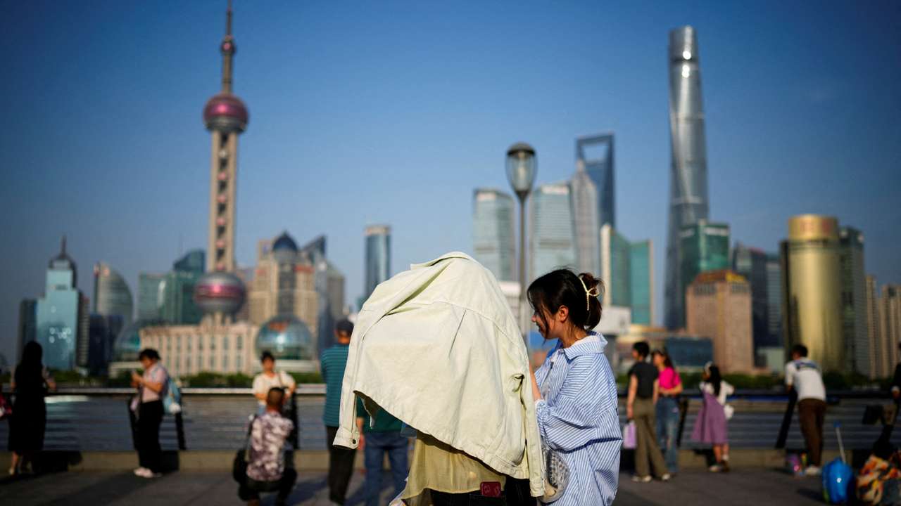 FILE PHOTO: A person uses clothing to protect themselves from the sun, as they walk on the Bund on a hot day, in Shanghai